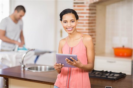 simsearch:6109-08488688,k - Young man ironing in the kitchen and his girlfriend using tablet at home Photographie de stock - Premium Libres de Droits, Code: 6109-08489073