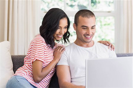 simsearch:6109-08489081,k - Smiling couple using laptop sitting on the couch at home Foto de stock - Sin royalties Premium, Código: 6109-08489091