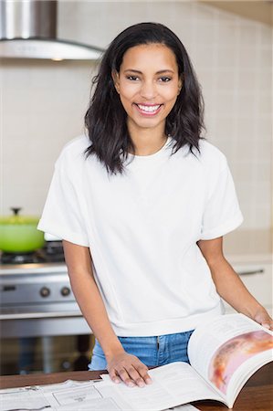 simsearch:6109-08488688,k - Smiling woman reading a magazine in the kitchen at home Stock Photo - Premium Royalty-Free, Code: 6109-08489016