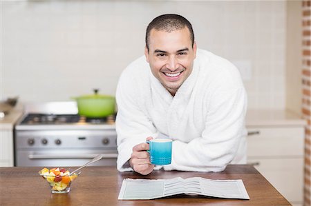Smiling man drinking coffee while reading a magazine in the kitchen at home Stock Photo - Premium Royalty-Free, Code: 6109-08489027