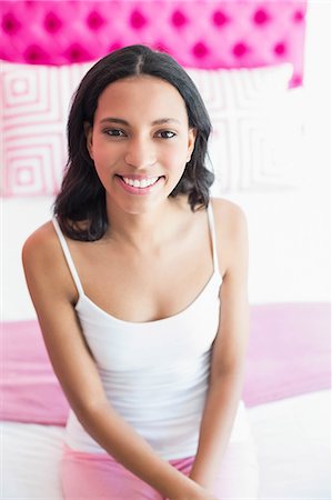 simsearch:6109-08489796,k - Brunette smiling sitting on a bed in a pink room at home Photographie de stock - Premium Libres de Droits, Code: 6109-08489188