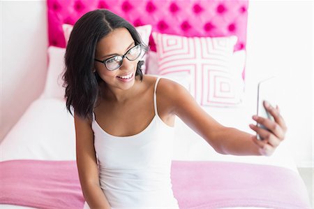 simsearch:6109-08390077,k - Smiling brunette taking picture with smartphone in pink bedroom Stock Photo - Premium Royalty-Free, Code: 6109-08489195