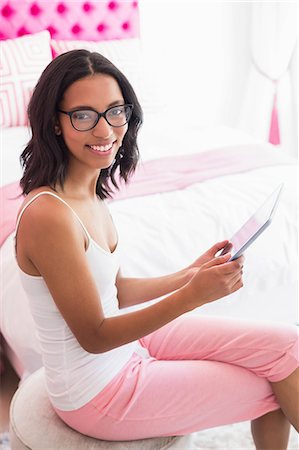 simsearch:6109-08435535,k - Smiling brunette using tablet in pink bedroom Stock Photo - Premium Royalty-Free, Code: 6109-08489198