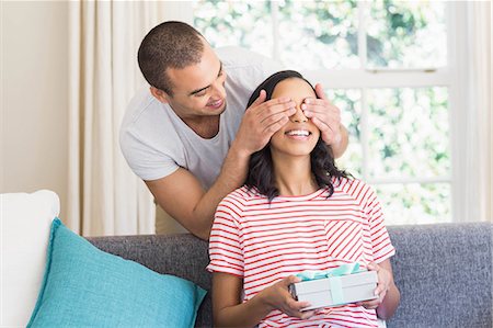eye - Happy couple offering a gift on the couch at home Stock Photo - Premium Royalty-Free, Code: 6109-08489107