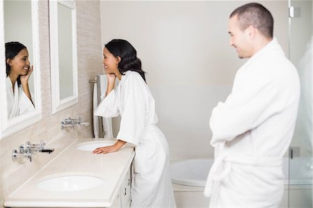 simsearch:6109-08435552,k - Smiling couple in bathrobe looking at mirror in bathroom Fotografie stock - Premium Royalty-Free, Codice: 6109-08489210