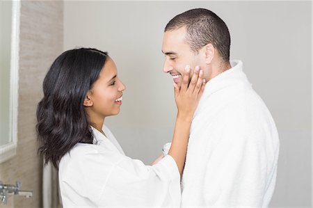 simsearch:6109-08435535,k - Smiling brunette putting on her husband cream Stock Photo - Premium Royalty-Free, Code: 6109-08489215