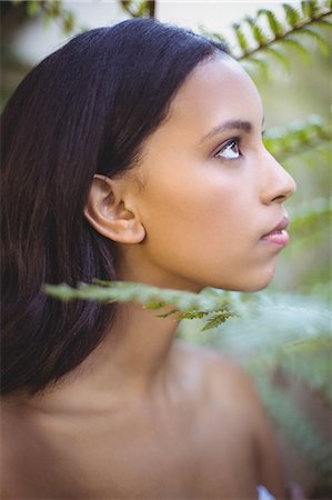Portrait of a pretty woman looking through leaves outside Stock Photo - Premium Royalty-Free, Code: 6109-08489234