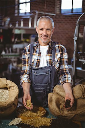 Happy brewer smiling at camera showing grains at the local brewery Stock Photo - Premium Royalty-Free, Code: 6109-08489370