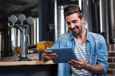 Handsome man using tablet computer in a pub Stock Photo - Premium Royalty-Free, Code: 6109-08489496