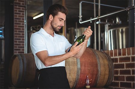 simsearch:6109-08489564,k - Handsome brewer checking at a wine bottle in a brewery Photographie de stock - Premium Libres de Droits, Code: 6109-08489528