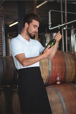 Handsome brewer checking at a wine bottle in a brewery Stock Photo - Premium Royalty-Free, Code: 6109-08489529