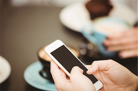 person typing restaurant - Friends looking at smartphone in cafe Stock Photo - Premium Royalty-Free, Code: 6109-08489748