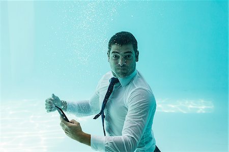 Businessman sending text underwater in swimming pool Photographie de stock - Premium Libres de Droits, Code: 6109-08489756