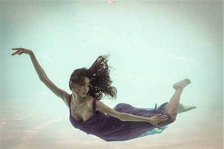 Brunette in evening gown swimming in pool underwater Foto de stock - Sin royalties Premium, Código: 6109-08489780