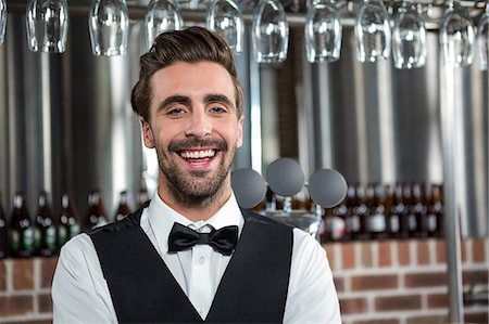 simsearch:6109-08489715,k - Handsome barman smiling at camera in a pub Stock Photo - Premium Royalty-Free, Code: 6109-08489703