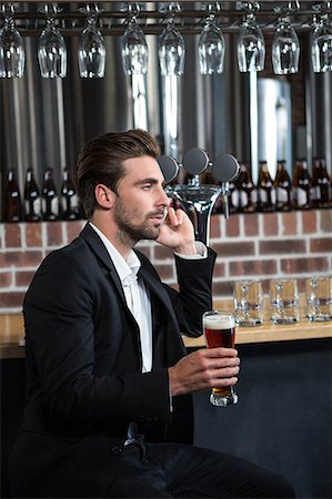 stylish businessman leaning - Handsome businessman holding a pint in a pub Foto de stock - Sin royalties Premium, Código: 6109-08489718