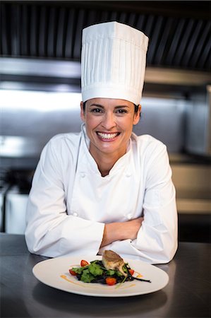 Happy chef showing her dish in a commercial kitchen Photographie de stock - Premium Libres de Droits, Code: 6109-08489859
