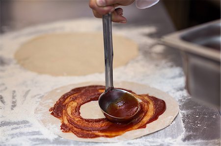 sauce in ladel - Pizza chef put sauce on base in a commercial kitchen Stock Photo - Premium Royalty-Free, Code: 6109-08489881