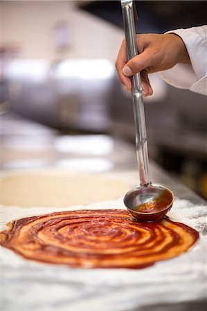 Pizza chef put sauce on base in a commercial kitchen Photographie de stock - Premium Libres de Droits, Code: 6109-08489882