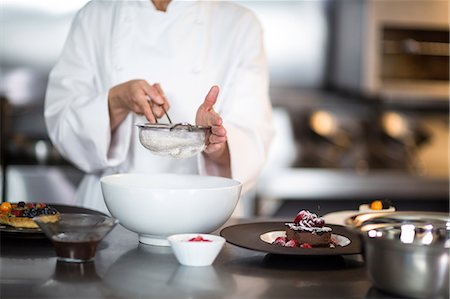 simsearch:6109-08489861,k - Chef putting finishing touch on dessert in a commercial kitchen Stock Photo - Premium Royalty-Free, Code: 6109-08489809