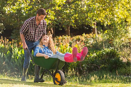 simsearch:400-08116305,k - Man pushing his girlfriend in a wheelbarrow on a sunny day Stock Photo - Premium Royalty-Free, Code: 6109-08434598