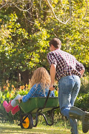 simsearch:400-07927044,k - Rear view of man pushing his girlfriend in a wheelbarrow on a sunny day Stock Photo - Premium Royalty-Free, Code: 6109-08434599
