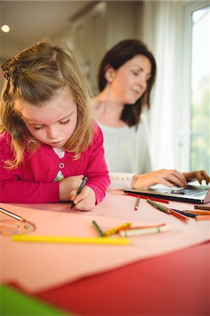 Mother on laptop while daughter drawing at home Stock Photo - Premium Royalty-Free, Code: 6109-08434642