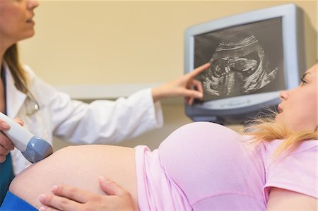 doctor smiling with pregnant woman - Doctor showing ultrasound scan to her patient at the ultrasound clinic Stock Photo - Premium Royalty-Free, Code: 6109-08434624