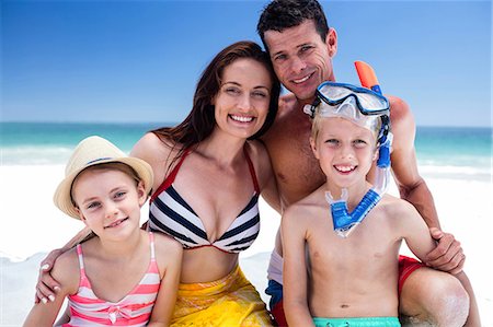 Cute family posing for camera with boy wearing snorkeling equipment on the beach Photographie de stock - Premium Libres de Droits, Code: 6109-08434792