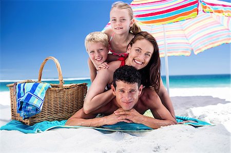 swimsuit sunbathing - Cute family lying on towels on the beach Stock Photo - Premium Royalty-Free, Code: 6109-08434795