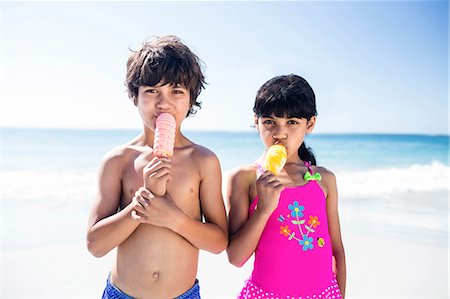 Cute siblings eating ice creams on the beach Stock Photo - Premium Royalty-Free, Code: 6109-08434824