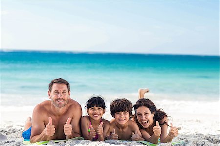 Cute family lying on towels with thumbs up on the beach Photographie de stock - Premium Libres de Droits, Code: 6109-08434833