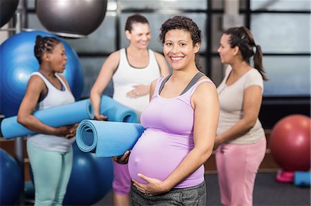 pregnant black women white man - Smiling pregnant woman holding exercise mat at the leisure center Stock Photo - Premium Royalty-Free, Code: 6109-08434935