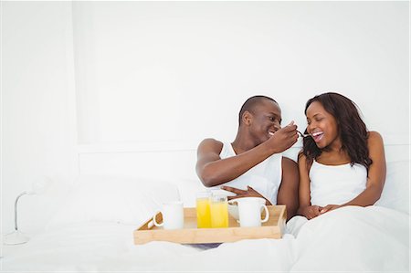 simsearch:6109-08435522,k - Ethnic couple having breakfast in their bed Photographie de stock - Premium Libres de Droits, Code: 6109-08435253