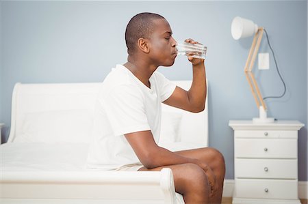 simsearch:6109-08489191,k - Handsome man drinking water sitting on his bed Fotografie stock - Premium Royalty-Free, Codice: 6109-08435208