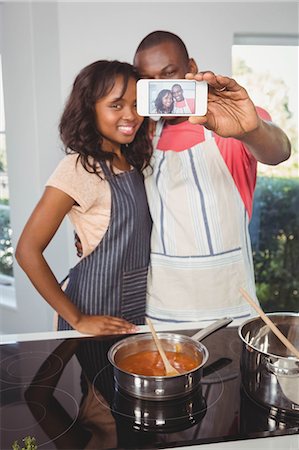 simsearch:6109-08390077,k - Ethnic couple taking selfie in the kitchen Foto de stock - Sin royalties Premium, Código: 6109-08435397