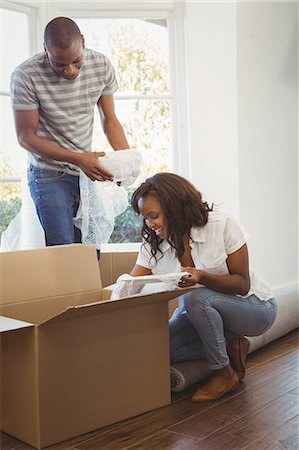 Ethnic couple unwrapping their stuff in boxes in their new house Stock Photo - Premium Royalty-Free, Code: 6109-08435329