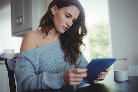 sweaters - Beautiful brunette using tablet in the living room at home Foto de stock - Sin royalties Premium, Código: 6109-08435582