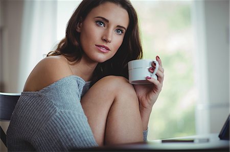 suéters - Thoughtful beautiful brunette using tablet while drinking coffee in the living room at home Foto de stock - Sin royalties Premium, Código: 6109-08435585