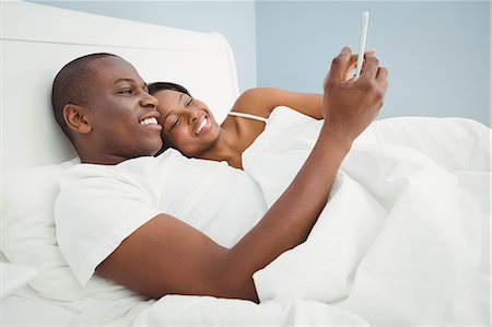 simsearch:6109-07497402,k - Ethnic couple using smartphone in bed Foto de stock - Sin royalties Premium, Código: 6109-08435502