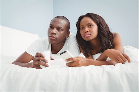simsearch:6109-08435383,k - Ethnic couple watching tv in bed Stock Photo - Premium Royalty-Free, Code: 6109-08435520