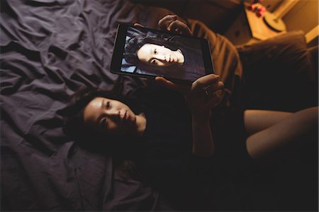 simsearch:6109-08435535,k - Brunette taking selfie with her tablet lying on the bed at home Stock Photo - Premium Royalty-Free, Code: 6109-08435641