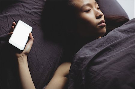 simsearch:6109-08435535,k - Brunette sleeping on the bed with smartphone at home Stock Photo - Premium Royalty-Free, Code: 6109-08435644