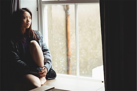 simsearch:6109-08390353,k - Brunette sitting on the edge of the window at home Stock Photo - Premium Royalty-Free, Code: 6109-08435652