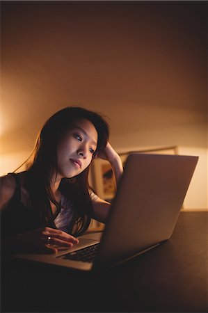 simsearch:6109-08390353,k - Brunette using laptop on desk at home Stock Photo - Premium Royalty-Free, Code: 6109-08435656