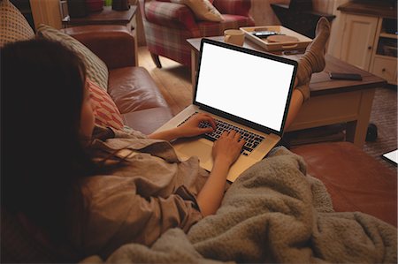 simsearch:6109-08390353,k - Brunette using laptop sitting on the sofa at home Stock Photo - Premium Royalty-Free, Code: 6109-08435662