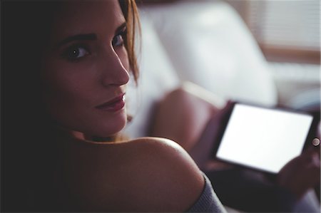 simsearch:6109-08390544,k - Beautiful brunette using tablet sitting on the couch at home Stock Photo - Premium Royalty-Free, Code: 6109-08435601
