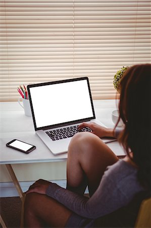 phone young woman at home - Brunette using laptop and smartphone sitting at her desk Stock Photo - Premium Royalty-Free, Code: 6109-08435602