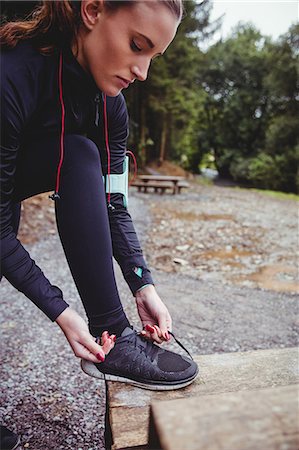 simsearch:6109-08435603,k - Fit brunette with armband tying her shoe lace in the woods Stock Photo - Premium Royalty-Free, Code: 6109-08435604