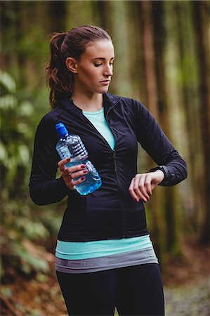 Fit brunette holding bottle and check her heart rate in the woods Photographie de stock - Premium Libres de Droits, Code: 6109-08435613